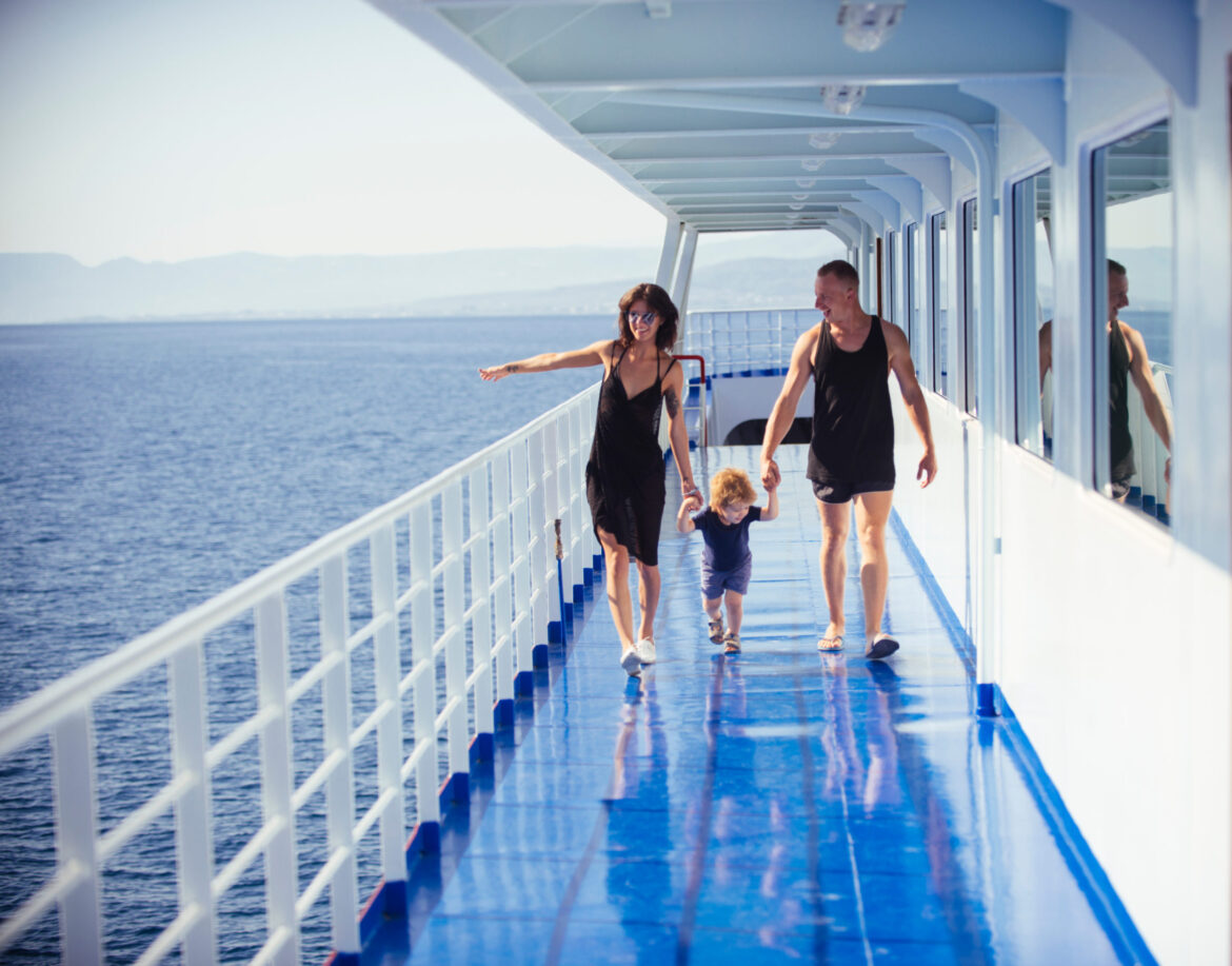 Happy family with cute son on summer vacation. Family travelling on cruise ship on sunny day. Family rest concept. Father, mother and child walk on deck of cruise liner with sea on background.